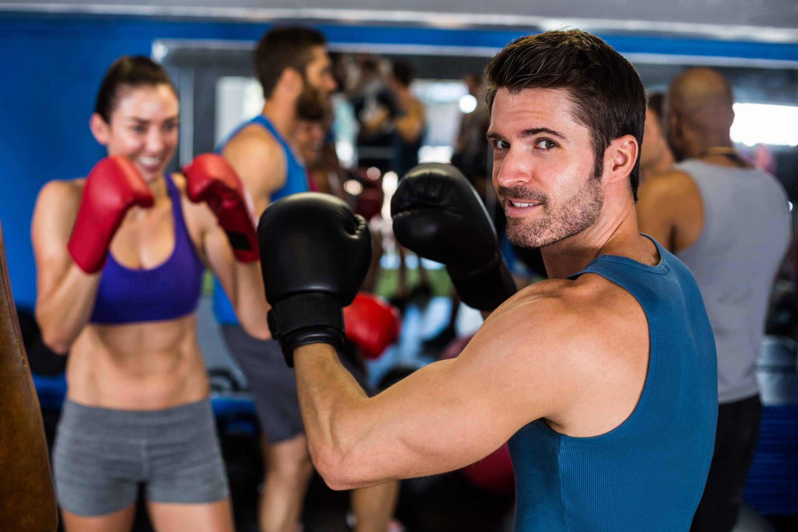 Portrait of smiling athlete boxing with woman in gym